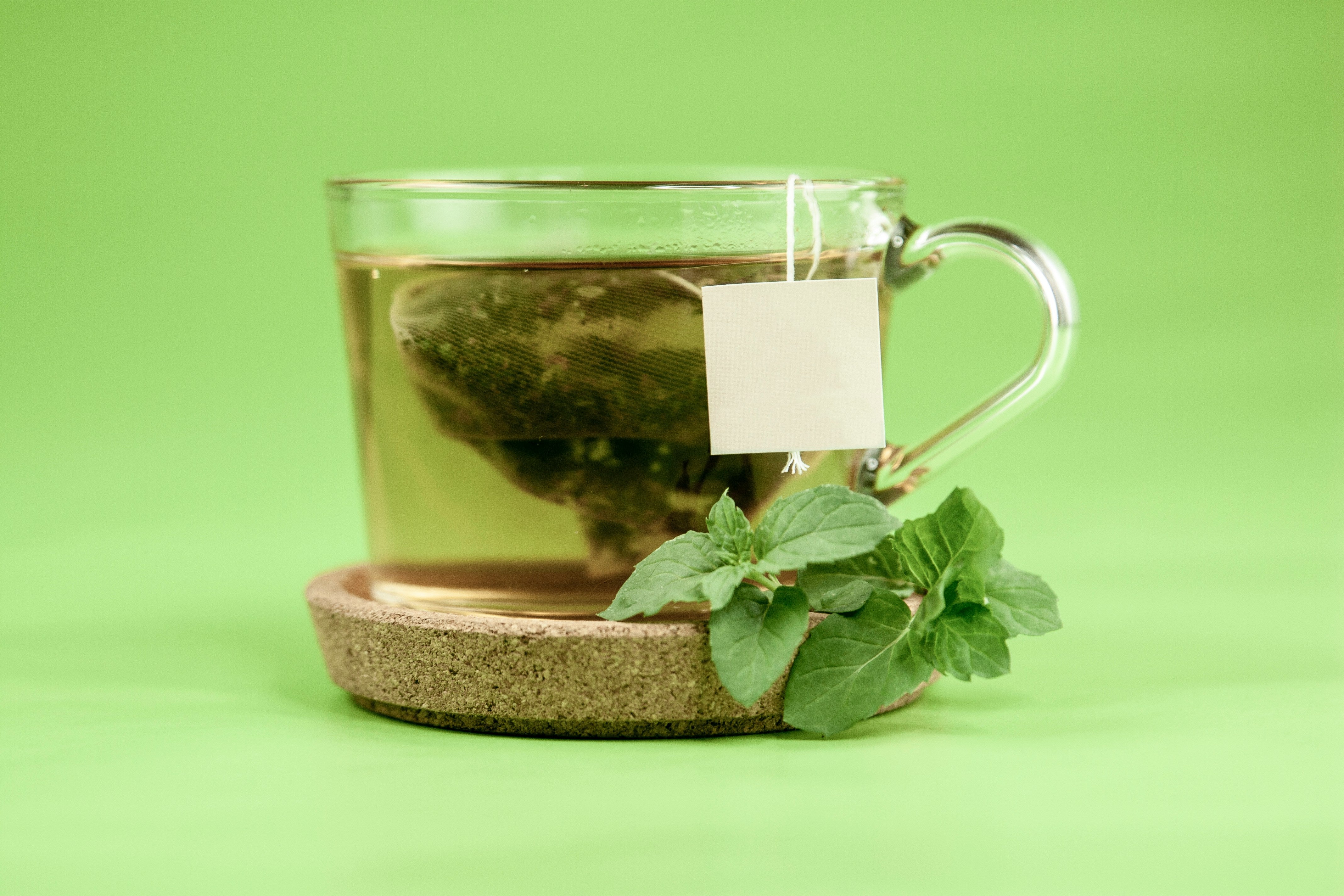 Clear glass mug of tea with green leaves
